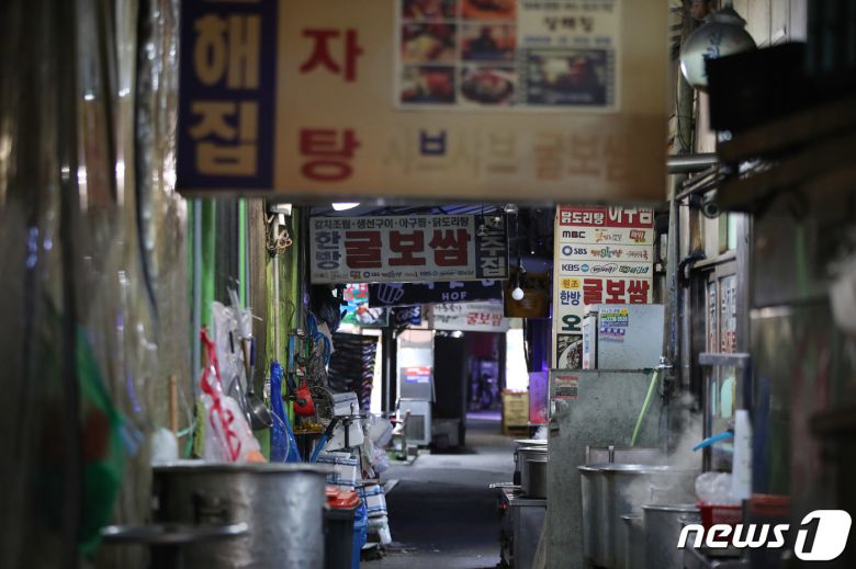 코로나피해자영업총연합(코자총)이 정부의 방역지침 강화에 항의해 간판과 입간판을 끄는 소등 시위를 시작한 27일 저녁 서울 도심의 먹자골목에서 상인들이 소등 시위에 참여하고 있다. 코자총 소속 자영업자들은 오늘과 내일 이틀간 오후 5시부터 4시간 동안 건물 노출 간판과 입간판을 소등하고 영업하는 시위를 진행한다고 밝혔다. 2021.12.27/뉴스1 © News1 박정호 기자