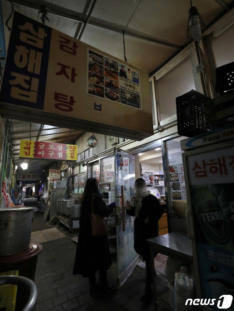 코로나피해자영업총연합(코자총)이 정부의 방역지침 강화에 항의해 간판과 입간판을 끄는 소등 시위를 시작한 27일 저녁 서울 도심의 먹자골목에서 상인들이 소등 시위에 참여하고 있다. 코자총 소속 자영업자들은 오늘과 내일 이틀간 오후 5시부터 4시간 동안 건물 노출 간판과 입간판을 소등하고 영업하는 시위를 진행한다고 밝혔다. 2021.12.27/뉴스1 © News1 박정호 기자