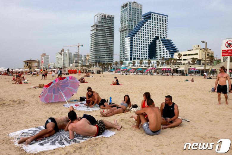 이스라엘이 높은 비중의 백신 접종 달성 직후 코로나19 극복 목전에 다가갔던 지난 4월 사람들이 마스크를 쓰지 않은 채 해변에서 일광욕을 즐기던 모습. 당시 번진 팬데믹 극복 기대감은 이후 델타 변이 유행으로 무너졌지만, 최근 등장한 오미크론은 델타와 다룰 수 있다는 희망이 다시 번지기 시작했다. © AFP=뉴스1