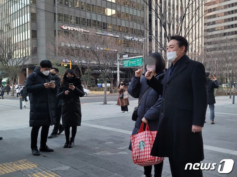 윤석열 국민의힘 대선후보가 6일 오전 서울 영등포구 여의도역 인근에서 출근길 인사를 하며 시민들과 사진을 찍고 있다. 2022.1.6/뉴스1 © News1 박기범 기자