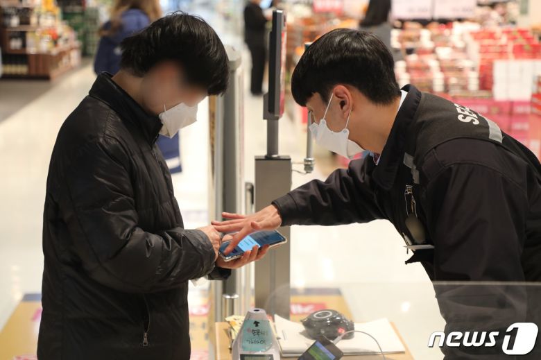 대형마트·백화점이 신종 코로나바이러스 감염증 방역패스 시행 대상으로 적용된 첫날인 10일 오전 10시30분 부산 한 대형마트 입구에 한 손님이 QR코드 형식의 방역패스 인증을 하기 위해 마트 직원의 설명을 듣고 있다.2022.1.10/뉴스1 © News1 노경민 기자
