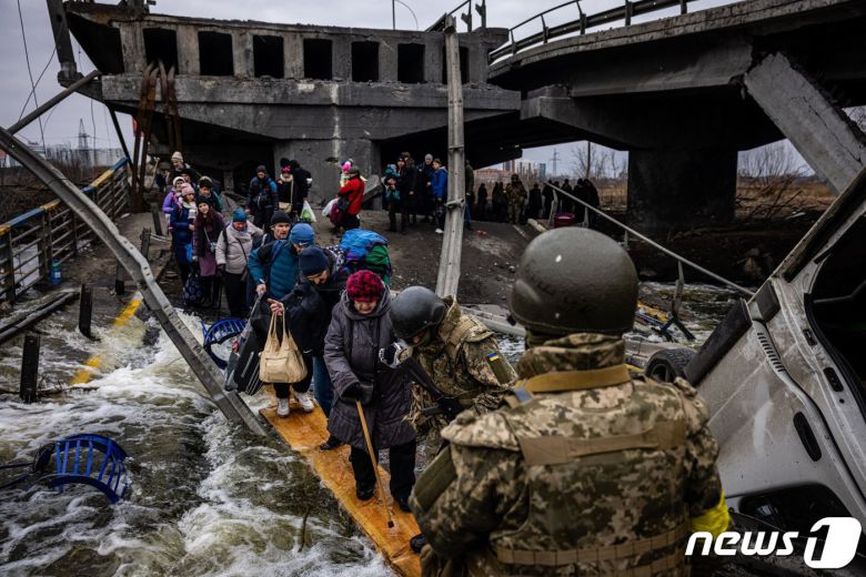 7일(현지시간) 우크라이나 수도 키이우 인근의 이르핀에서 주민들이 러시아 군의 공격을 받아 파괴된 다리를 건너 피란를 하고 있다. © AFP=뉴스1 © News1 우동명 기자
