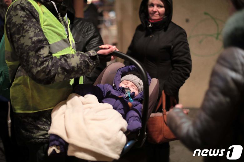지난 6일 우크라이나 접경 도시인 폴란드 프셰미실 중앙역에서 한 폴란드 군인이 르비우발 기차를 이용한 피란민을 도와 잠든 아기를 옮기는 모습. 2022.3.7/뉴스1 © News1 조태형 기자