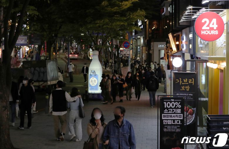 사회적 거리두기가 해제된 18일 저녁 서울 24시간 영업을 알리는 간판에 불이 켜진 홍대거리가 시민들로 붐비고 있다. 이날부터 신종 코로나바이러스 감염증(코로나19)으로 2년 넘게 시행됐던 거리두기 조치가 대부분 종료됐다. 영업시간, 사적모임, 행사·집회, 종교활동, 실내취식금지 등 마스크 착용을 제외한 모든 사회적 거리두기 조치를 해제했다. 2022.4.18/뉴스1 © News1 박세연 기자