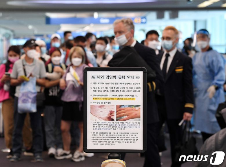 27일 오전 인천국제공항 제1터미널 입국장에 해외 입국자들이 검역을 받기 위해 대기하고 있다. 입국자들 앞에 원숭이두창 관련 안내문이 세워져 있다. (공동취재)2022.5.27/뉴스1 © News1 박세연 기자