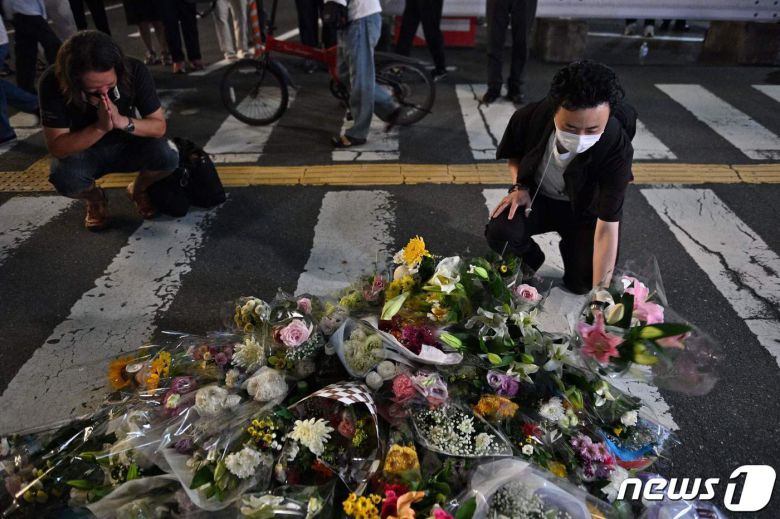 아베 신조(安倍晋三) 전 일본 총리가 총격 사망한 8일 사고 현장인 일본 나라 야마토사이다이지 역 외곽의 현장에서 시민들이 꽃을 놓는 임시 기념비 앞에서 슬퍼하고 있다. © AFP=뉴스1 © News1 임세영 기자