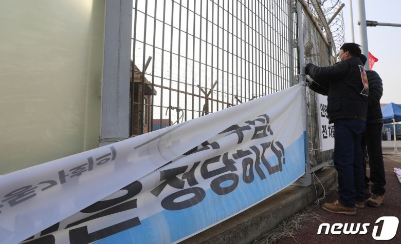 민주노총 공공운수노조 화물연대본부의 집단운송거부(총파업) 16일째를 끝으로 파업 종료를 결정한 9일 오후 경기 평택시 포승읍 평택항 인근에 설치된 현수막을 화물연대 조합원들이 철거하고 있다. 화물연대는 이날 총파업 철회 여부를 결정하기 위한 총투표를 진행했으며 투표 결과는 파업 종료로 가결됐다. 2022.12.9/뉴스1 ⓒ News1 김영운 기자