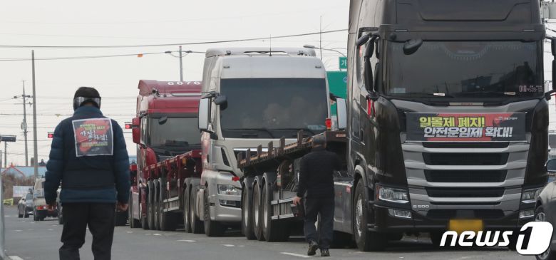 9일 민주노총 공공운수노조 화물연대의 파업철회 찬반투표 결과 파업종료로 가결 되면서 충남 당진시 현대글로비스 앞에서 파업 농성을 하던 화물연대 조합원이 화물차량에 부착한 '일몰제 폐지!, 안전운임제 확대' 플래카드 앞을 지나며 업무복귀를 하고 있다. 2022.12.9/뉴스1 ⓒ News1 김기남 기자