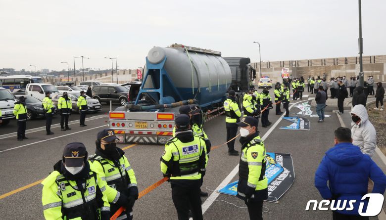 화물연대 총파업 후 처음으로 제주지역에 시멘트가 반입된 8일 오전 제주시 애월항에서 벌크시멘트트레일러(BCT) 차량이 시멘트를 싣고 이동하는 동안 화물연대 노조원들과 경찰이 대치하고 있다. 2022.12.8/뉴스1 ⓒ News1 오현지 기자