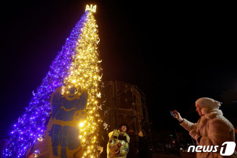 19일(현지시간) 우크라이나 수도 키이우 도심 소피아 광장에 크리스마스 트리가 점등되자 시민들이 나와 기념사진을 찍고 있다. 2022. 12. 19. ⓒ 로이터=뉴스1 ⓒ News1 최서윤 기자