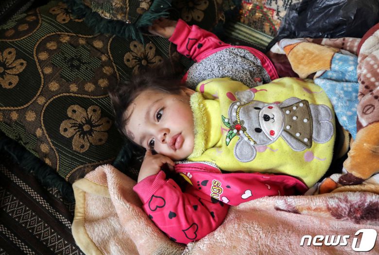 8일(현지시간) 시리아 잔다리스 마을의 붕괴 현장에서 살아남은 압둘라만 알리 알마무드의 막내 딸. 아이와 아버지는 막대기와 담요로 얼기설기 만든 임시 대피소로 몸을 피했다. ⓒ 로이터=뉴스1 ⓒ News1 권진영 기자