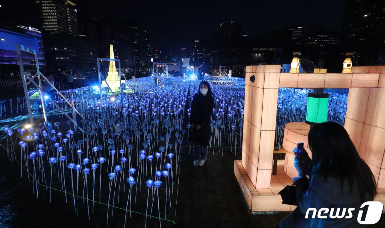 30일 오후 서울 종로구 광화문광장에서 열린 '광화에서 빛; 나이다'를 찾은 시민들이 불 밝힌 LED 장미를 배경으로 사진을 찍고 있다. 2023.3.30/뉴스1 ⓒ News1 김진환 기자