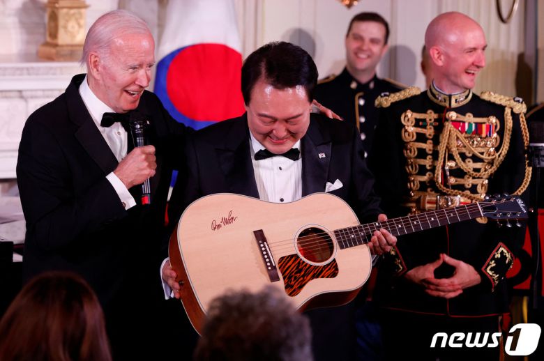 미국을 국빈 방문한 윤석열 대통령이 26일(현지시간) 워싱턴 DC 백악관에서 열린 국빈만찬에서 조 바이든 미국 대통령으로부터 가수 돈 맥클린의 친필 사인이 담긴 통기타를 선물 받고 있다. 2023.04.26. ⓒ 로이터=뉴스1 ⓒ News1 김성식 기자