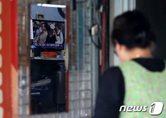 서울 시내 전통시장에서 한 상인이 장사를 준비하고 있는 가운데 더위 관련 뉴스가 거울에 비치고 있다. ⓒ News1 이동해 기자