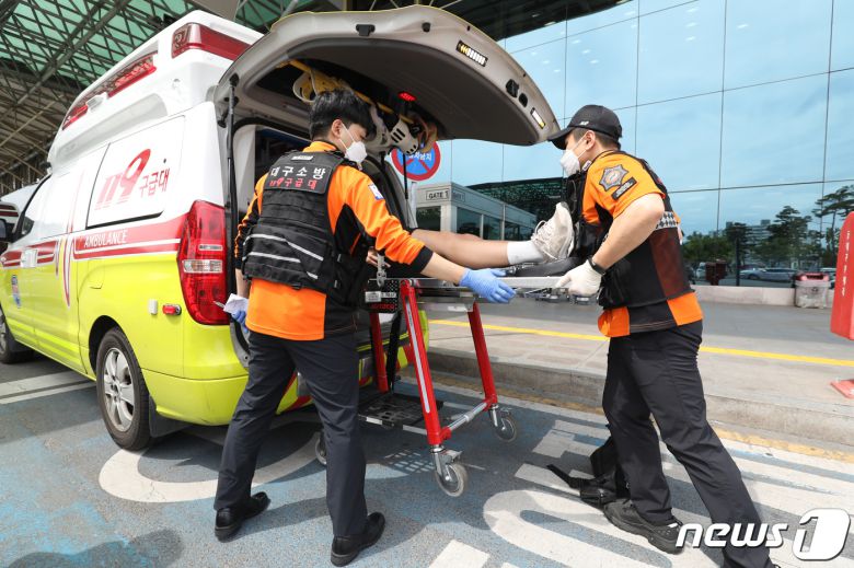 26일 오전 제주공항을 출발해 대구공항으로 향하던 아시아나 항공기에서 비행 중 문이 열리는 사고가 발생했다. 울산에서 열리는 제52회 전국소년체육대회에 참가하기 위해 비행기에 탑승했던 초·중학생 제주특별자치도 선수단 가운데 대구공항 도착 직후 고통을 호소하는 선수들을 119구조대가 병원으로 이송하기 위해 들것을 이용해 구급차로 옮기고 있다. 2023.5.26/뉴스1 ⓒ News1 공정식 기자