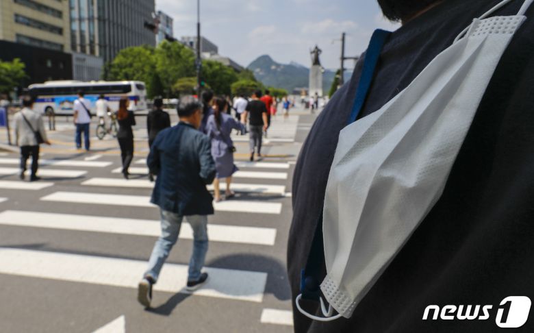 31일 서울 광화문네거리를 지나는 한 시민이 마스크를 벗고 있다. 정부는 6월 1일부터 신종 코로나바이러스 감염증(코로나19) 감염병 위기 경보 단계를 '심각'에서 '경계'로 내리고, 확진자에 대한 격리 의무폐지, 임시 선별검사소 운영종료 등 방역조치를 완화한다. 2023.5.31/뉴스1 ⓒ News1 김도우 기자