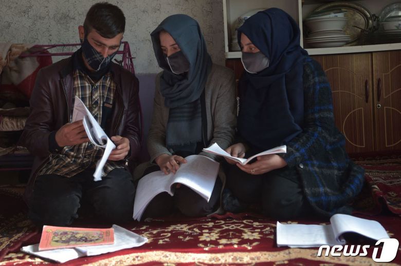 지난해 12월 아프가니스탄 수도 카불의 한 가정집에서 히잡을 착용한 마르와(가운데)가 오빠인 하미드(왼쪽)에게 가정 교육을 받고 있다. 마르와는 불과 몇 달 전만 해도 대학생이었지만 최근 탈레반 당국에 의해 여성이란 이유로 대학 교육을 금지 받았다. 2022.12.23. ⓒ AFP=뉴스1 ⓒ News1 김성식 기자