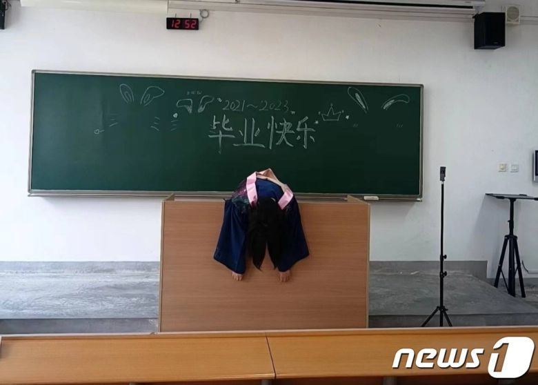 한 대학생이 교탁 위에 축 늘어져 있다. 칠판에는 '졸업축하'라는 글이 쓰여 있다. - 웨이보 갈무리