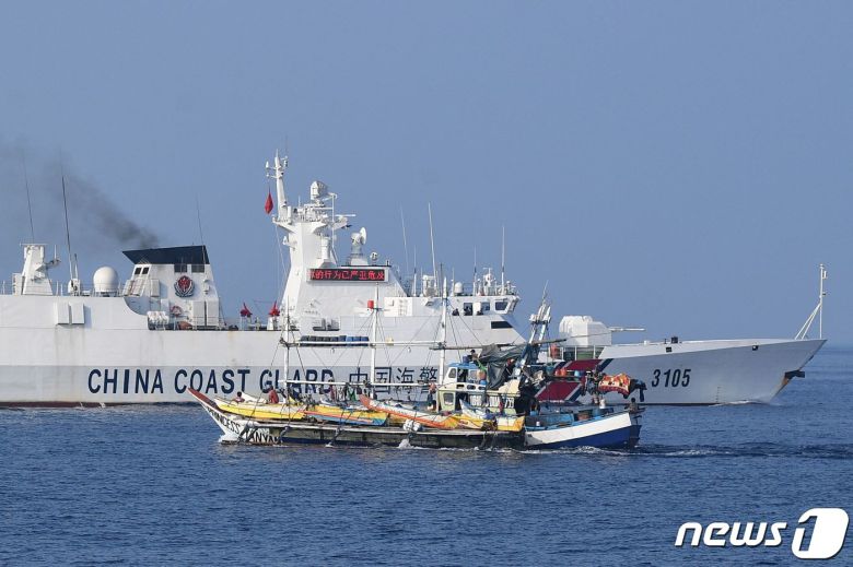 지난 20일(현지시간) 남중국해(서필리핀해) 스카버러 암초(중국명 황옌다오·필리핀명 바조데마신록) 인근에서 조업하는 필리핀 어선 옆으로 중국 해안경비대 함정이 지나가고 있다. 2023.9.25. ⓒ AFP=뉴스1 ⓒ News1 김기성 기자