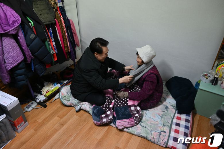 윤석열 대통령이 최강한파를 기록한 21일 서울 중랑구의 한 독거노인 가정을 방문해 어르신에게 방한용품을 선물하고 있다. (대통령실 제공) 2023.12.21/뉴스1 ⓒ News1 오대일 기자