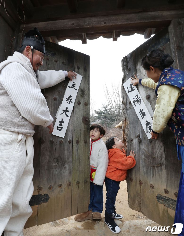 절기상 입춘(立春)을 사흘 앞둔 1일 경기 용인시 기흥구 한국민속촌에서 직원들과 아이들이 입춘대길(立春大吉)과 건양다경(建陽多慶)이라고 적은 입춘첩을 대문에 붙이고 있다. 입춘대길과 건양다경은 '봄이 시작되니 크게 길하고 경사스러운 일이 많이 생기길 기원한다'는 의미를 갖고 있다. 2024.2.1/뉴스1 ⓒ News1 김영운 기자