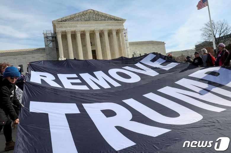 미국 워싱턴DC 연방대법원에서 8일(현지시간) 도널드 트럼프 전 미국 대통령의 콜로라도주 대선후보 자격 박탈 여부에 대한 재판이 열린 가운데, 일부 활동가들이 트럼프 전 대통령의 대선후보 자격 박탈을 요구하는 현수막을 들고 있다. 2024.02.08. ⓒ 로이터=뉴스1 ⓒ News1 김현 특파원