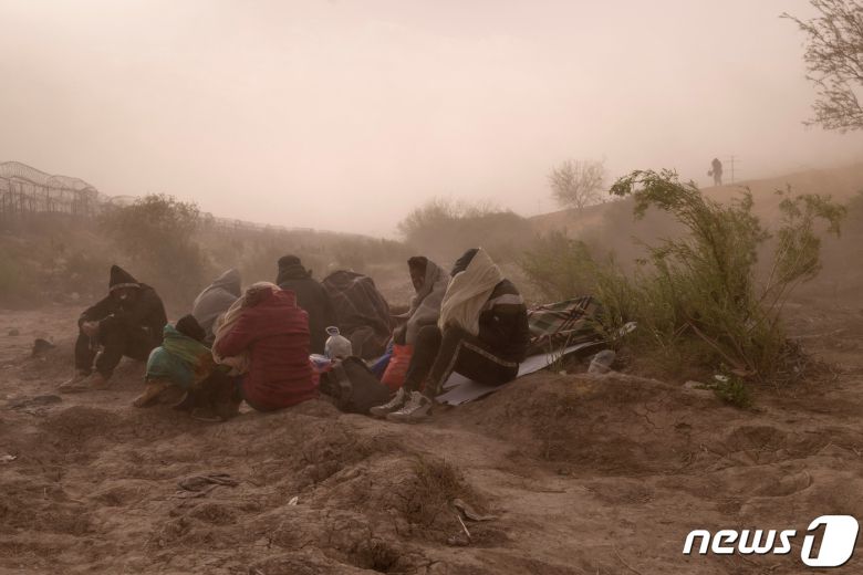 24일(현지시간) 미국 텍사스주 엘 파소에서 이민자들이 미국으로 들어가는 입구를 찾으려 강한 바람과 먼지를 견디고 있다. 2024.03.24 ⓒ 로이터=뉴스1 ⓒ News1 정지윤 기자