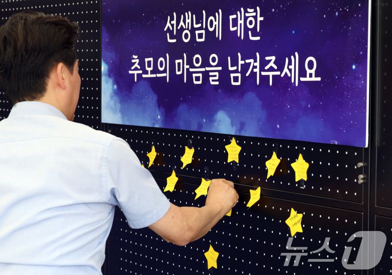 서이초 교사 순직 1주기(18일)를 앞둔 15일 서울 종로구 서울시교육청에 마련된 서이초 교사 1주기 추모 공간에서 교육청 직원이 추모의 마음을 담아 쓴 글을 붙이고 있다. 2024.7.15/뉴스1 ⓒ News1 박정호 기자