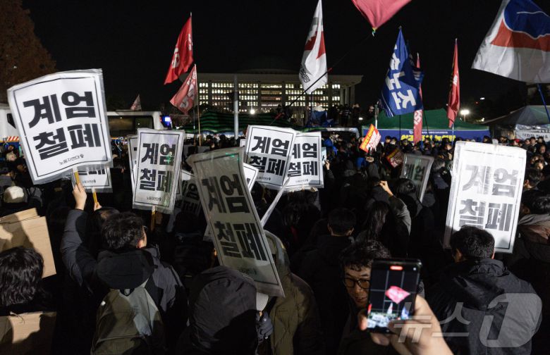 윤석열 대통령의 비상계엄 해제 요구 결의안이 국회 본회의에서 통과된 4일 새벽 서울 여의도 국회 정문 앞에 모인 시민들이 모여 있다. 여야는 이날 본회의에서 재석 190명 중 찬성 190명으로 비상계엄 해제 요구 결의안을 가결 처리했다. 이에 따라 계엄령 선포는 무효가 됐다고 국회의장실은 설명했다. 2024.12.4/뉴스1 ⓒ News1 이재명 기자