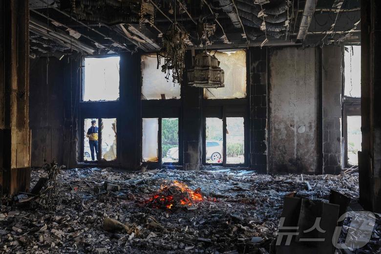 8일(현지시간) 시리아 다마스쿠스 대통령궁의 한 방이 완전히 불탄 모습을 한 남성이 지켜보고 있다. 24년간 철권통치를 이어온 바샤르 알 아사드 시리아 대통령은 13년간의 내전 끝에 반군의 공세에 밀려 가족과 함께 시리아를 떠나 러시아 모스크바로 피신했다. 2024.12.08 ⓒ AFP=뉴스1 ⓒ News1 김지완 기자