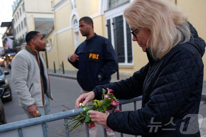 1일(현지시간) 미국 루이지애나주 뉴올리언스에서 새해맞이 행사 중 트럭을 몰고 군중을 향해 돌진해 사람들이 사망한 사건이 발생한 후 사만다 맥거번이 꽃다발을 보안 장벽에 묶고 있다. ⓒ 로이터=뉴스1 ⓒ News1 류정민 특파원