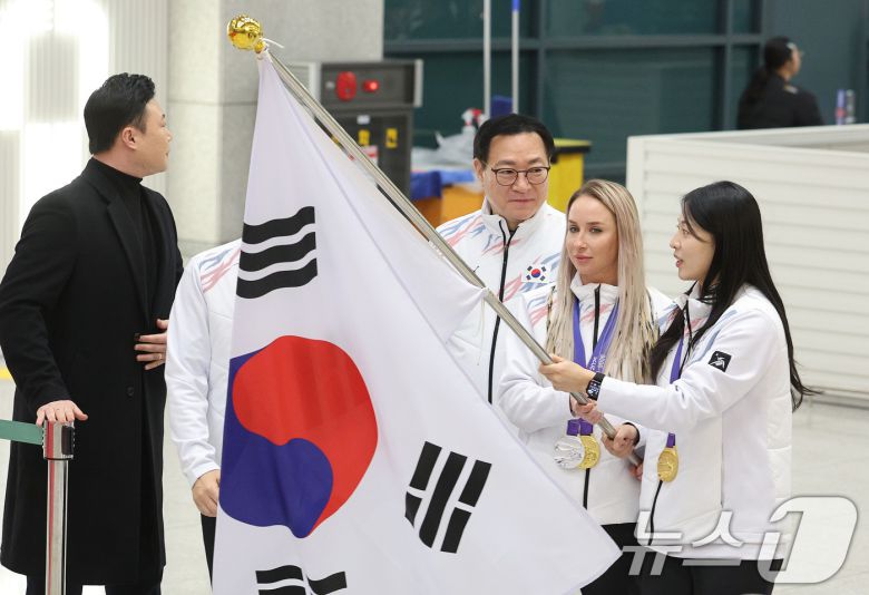 귀화 선수로서 한국 바이애슬론 사상 첫 동계아시안게임 금메달을 획득한 예카테리나 압바꾸모바(왼쪽)와 여자컬링에서 금메달을 차지한 김민지가 15일 오후 인천국제공항 1터미널 귀국장에서 열린 2025 하얼빈 동계 아시안게임 한국 선수단 귀국 환영 행사에 태극기를 들고 입장하고 있다. 8년 만에 열린 이번 대회에 한국은 총 222명의 선수단을 파견해 금메달 16개, 은메달 15개, 동메달 14개를 수확하며 개최국 중국(금 32·은 27·동 25)에 이어 종합 2위를 차지했다. 2025.2.15/뉴스1 ⓒ News1 신웅수 기자