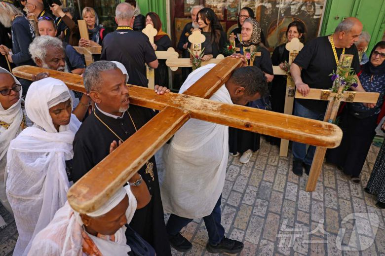 18일(현지시간) 열린 성금요일 행사에서 큰 나무 십자가를 든 팔레스타인 정교회 소속 기독교인들이 예루살렘 구시가지를 걷고 있다. ⓒ AFP=뉴스1