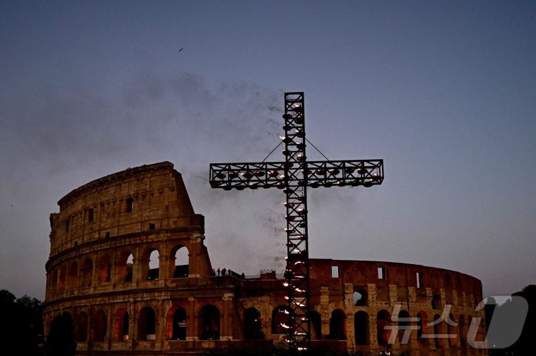 18일(현지시간) 이탈리아 로마 성금요일 행사의 일환으로 한 노동자가 십자가의 길(십자가를 통해) 콜로세움 밖의 십자가에 불을 붙이고 있다. ⓒ AFP=뉴스1