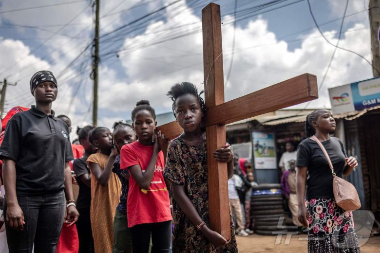 18일(현지시간) 케냐 나이로비의 키베라 비공식 정착촌에서 성금요일 행사의 일환으로 열린 그리스도의 수난 재현 행사에서 젊은 기독교 신자들이 십자가를 들고 행진하고 있다. ⓒ AFP=뉴스1