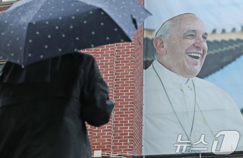 22일 오전 서울 중구 명동성당에서 수녀님이 건물 외벽에 붙은 프란치스코 교황의 사진을 바라보고 있다.  2025.4.22/뉴스1 ⓒ News1 장수영 기자