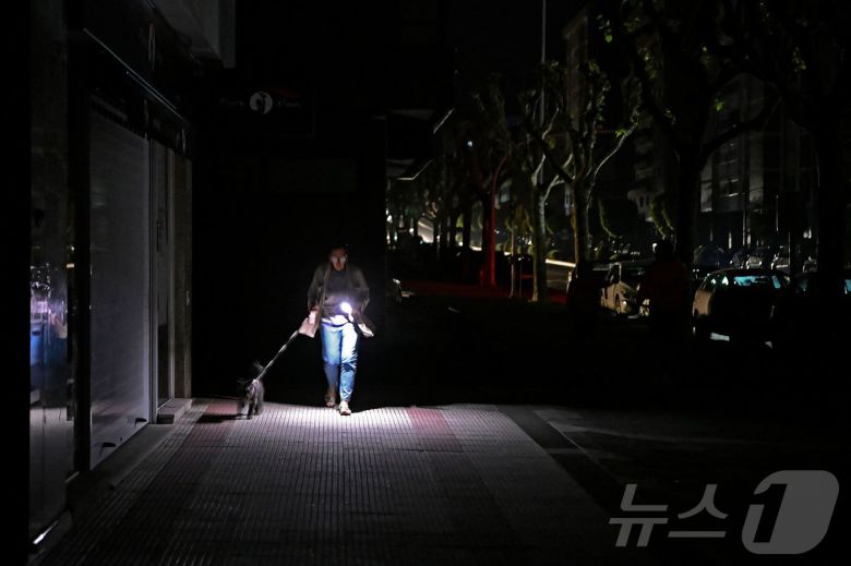 이베리아 반도에 대규모 정전이 발생한 28일(현지시간) 스페인 비고에서 한 시민이 어둠속에서 반려견과 산책을 하고 있다. ⓒ AFP=뉴스1