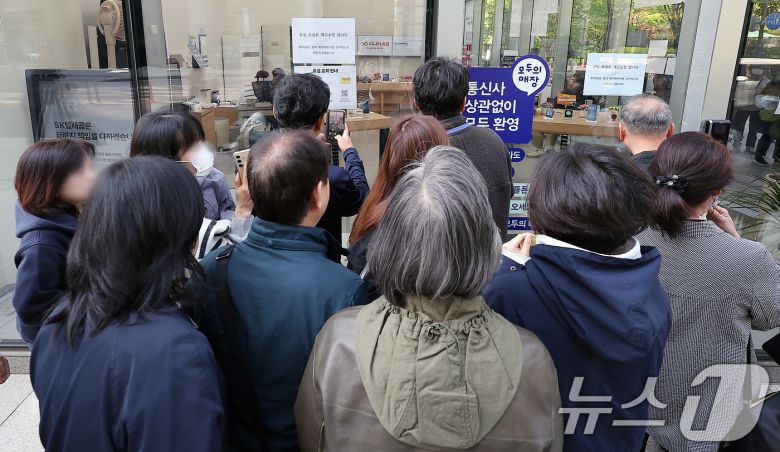 SK텔레콤 가입자 유심(USIM) 정보 해킹 사고 관련 유심 무료교체 서비스 이틀 째인 29일 오전 서울 종로구 T월드 직영 매장 앞에서 번호표를 받지 못한 고객들이 온라인 예약을 하고 있다. 2025.4.29/뉴스1 ⓒ News1 김진환 기자