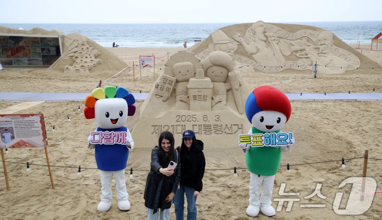 제21대 대통령선거를 앞둔 15일 오후 부산 해운대해수욕장에서 정책·공약에 대한 관심과 투표 참여를 높이기 위해 부산시선관위의 '모래로 만나는 대통령선거' 홍보 캠페인이 진행되는 가운데 외국인 관광객들이 모래작품 앞에서 셀카를 찍고 있다. 2025.5.15/뉴스1 ⓒ News1 윤일지 기자
