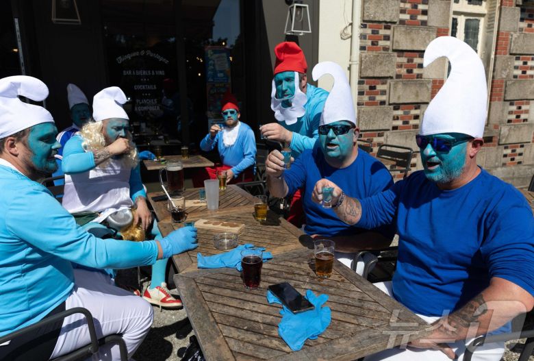 프랑스 서부 랑데르노의 한 카페 테라스에서 17일(현지시간) 스머프 복장을 한 스머프 세계 도전 참가자들이 파란색 술이 담긴 잔을 들고 있다. ⓒ AFP=뉴스1 ⓒ News1 권영미 기자