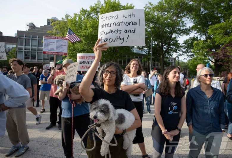 27일(현지시간) 미국 매사추세츠주(州) 보스턴에 있는 하버드 대학교 캠퍼스에서 유학생을 지지하는 집회가 열렸다. 한 집회 참여자가 '국제 유학생과 교수진과 함께한다'는 플래카드를 들고 있는 모습. 25.05.27 ⓒ AFP=뉴스1 ⓒ News1 김예슬 기자