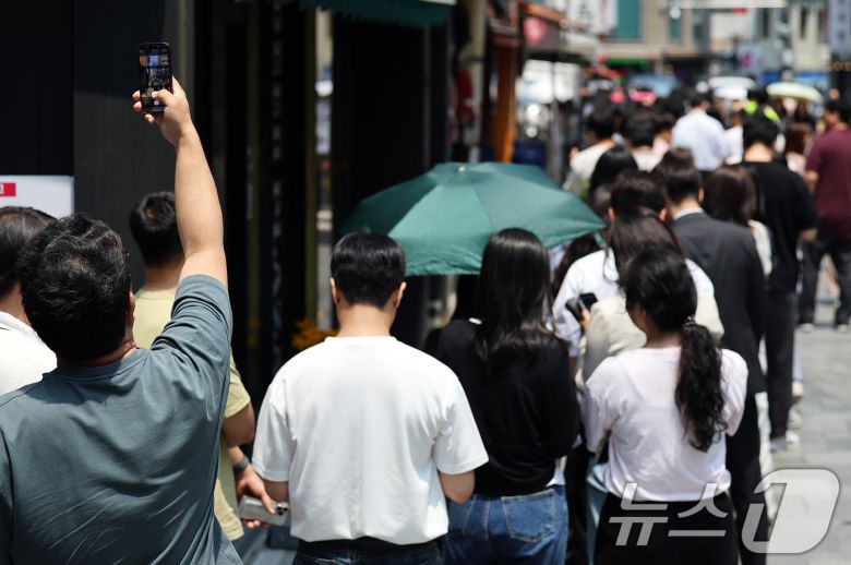 제21대 대통령선거 사전투표 첫 날인 29일 서울 중구 소공동주민센터에 마련된 투표소에서 직장인들이 점심시간 투표를 위해 대기하며 길게 늘어선 투표 인파를 스마트폰에 담고 있다. ⓒ News1 오대일 기자