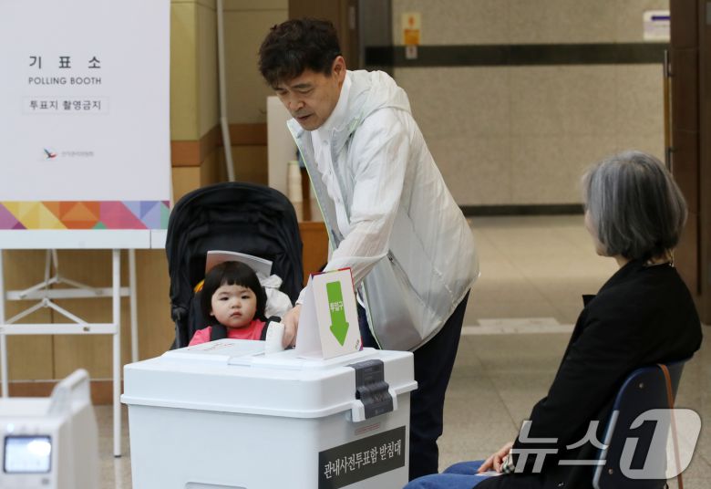 제21대 대통령선거 사전투표 둘째 날인 30일 오전 부산 남구청 대강당에 마련된 사전투표소에서 유모차에 탄 아이가 아빠의 투표하는 모습을 지켜보고 있다. 2025.5.30/뉴스1 ⓒ News1 윤일지 기자