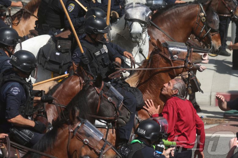 14일(현지시간) 미국 캘리포니아주 로스앤젤레스(LA)에서 도널드 트럼프 미국 대통령의 정책과 이민 정책에 반대하는 '노 킹스'(No Kings) 시위에서 한 시위 참여자가 기마 경찰을 막아 서고 있다. 2025.06.14 ⓒ 로이터=뉴스1 ⓒ News1 류정민 특파원
