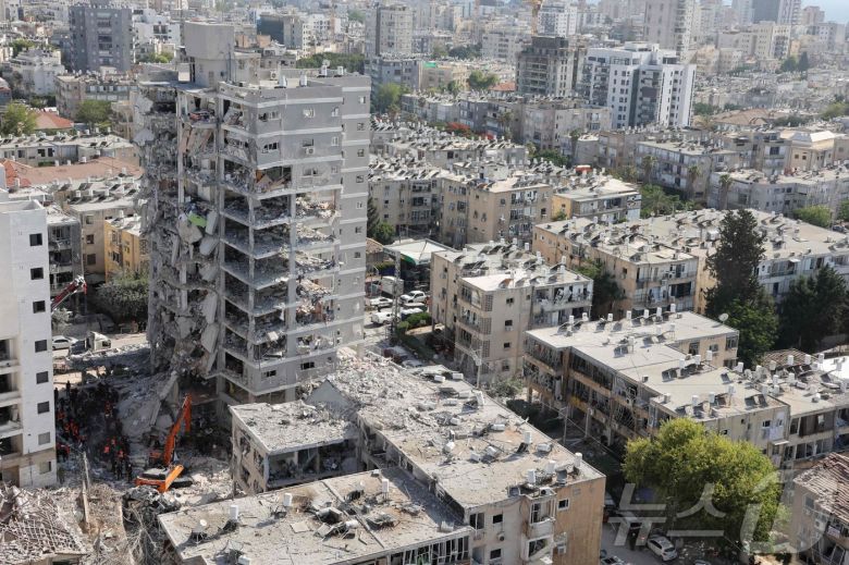 15일(현지시간) 이스라엘 바트얌에서 구조대원들이 이란의 미사일 공격으로 파괴된 잔해를 수색하고 있다.ⓒ AFP=뉴스1