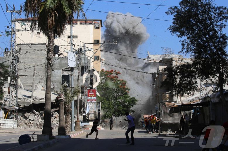 15일(현지시간) 가자 지구에 이스라엘 공습으로 팔레스타인 난민들이 폭격을 피해 달려가고 있다. ⓒ AFP=뉴스1