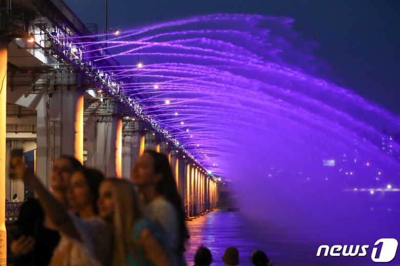 서울 지역 낮 최고기온이 33도를 넘어서는 등 전국적으로 무더위가 나타난 26일 오후 서울 서초구 반포한강공원에서 외국인 관광객들과 시민들이 반포대교 달빛무지개분수를 감상하며 열대야를 이겨내고 있다. 2022.7.26/뉴스1 ⓒ News1 민경석 기자