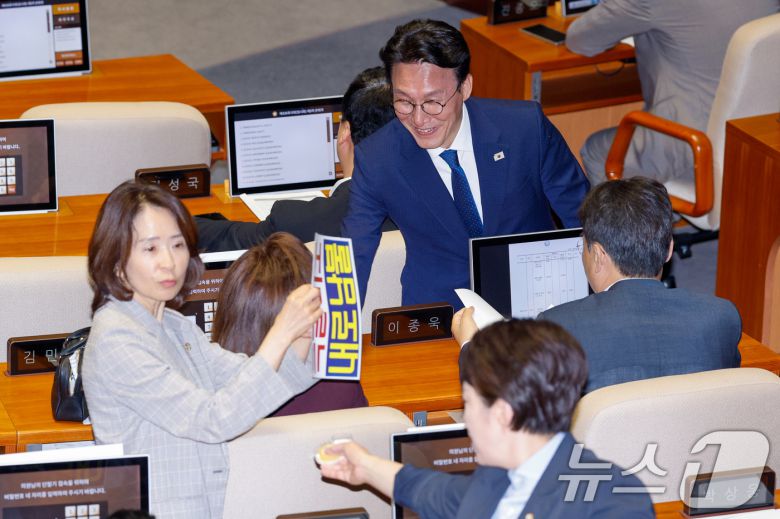 김민석 신임 국무총리가 4일 오후 서울 여의도 국회에서 제426회국회(임시회) 제5차 본회의에 앞서 국민의힘 의원석으로 가 인사하는 가운데 최수진 원내대변인이 '특활비도 내로남불'이라고 적힌 피켓을 의원석에 붙이고 있다. 2025.7.4/뉴스1 ⓒ News1 안은나 기자