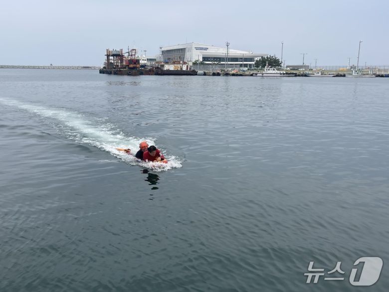 지난 7일 오후 강원 속초 속초해경 전용부두 인근 해상에서 진행된 구조·구급 대응 훈련에 동참한 기자. 결국 요구조자가 돼 구조대원에 이끌려 물 밖으로 나오고 있다.(속초해경 제공, 재판매 및 DB 금지) 2025.7.8/뉴스1