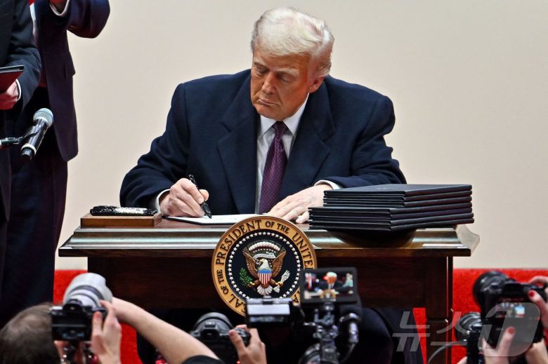 도널드 트럼프 미국 대통령이 두 번째 임기 취임 첫날인 올해 1월 20일(현지시간) 워싱턴 '캐피털원 아레나'에서 열린 제47대 대통령 취임 축하 퍼레이드에 참석해 지지자들 앞에서 행정명령에 서명하고 있다. 2025.01.21 ⓒ AFP=뉴스1 ⓒ News1 우동명 기자